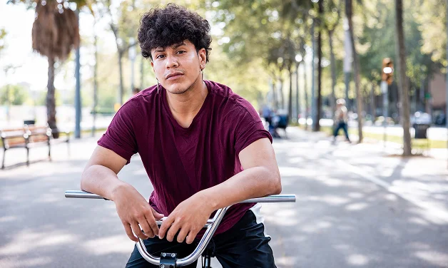 Joven ciclista sentado en su bicicleta mirando a la cámara.