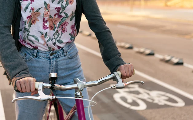 Ciclista sujetando el manillar junto a un carril bici pintado en el pavimento.