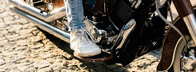 Pie de un motociclista sobre el estribo de la motocicleta.