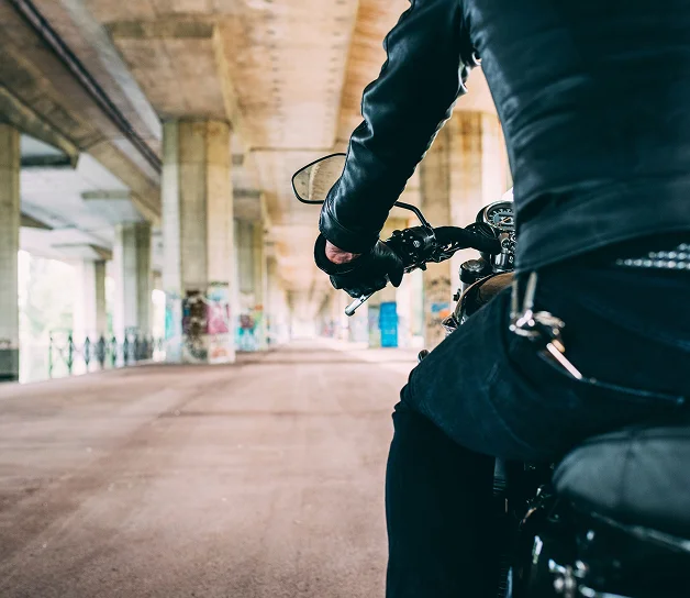 Motociclista conduciendo por una vía urbana bajo un puente.