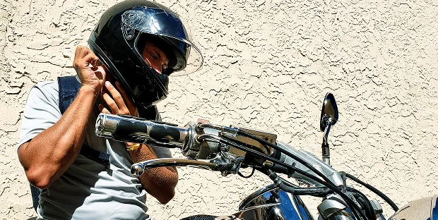 Motociclista colocándose el casco antes de conducir.
