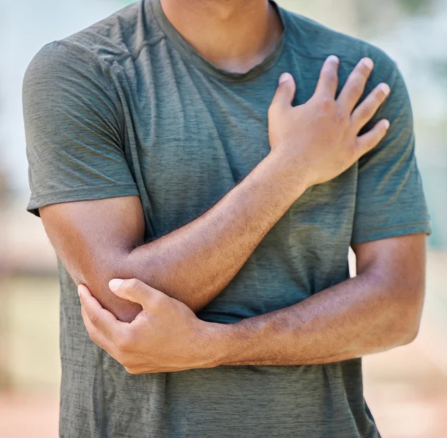 Hombre sosteniéndose el hombro con dolor tras sufrir una lesión personal.