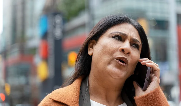 Mujer preocupada hablando por teléfono con la aseguradora en la calle.