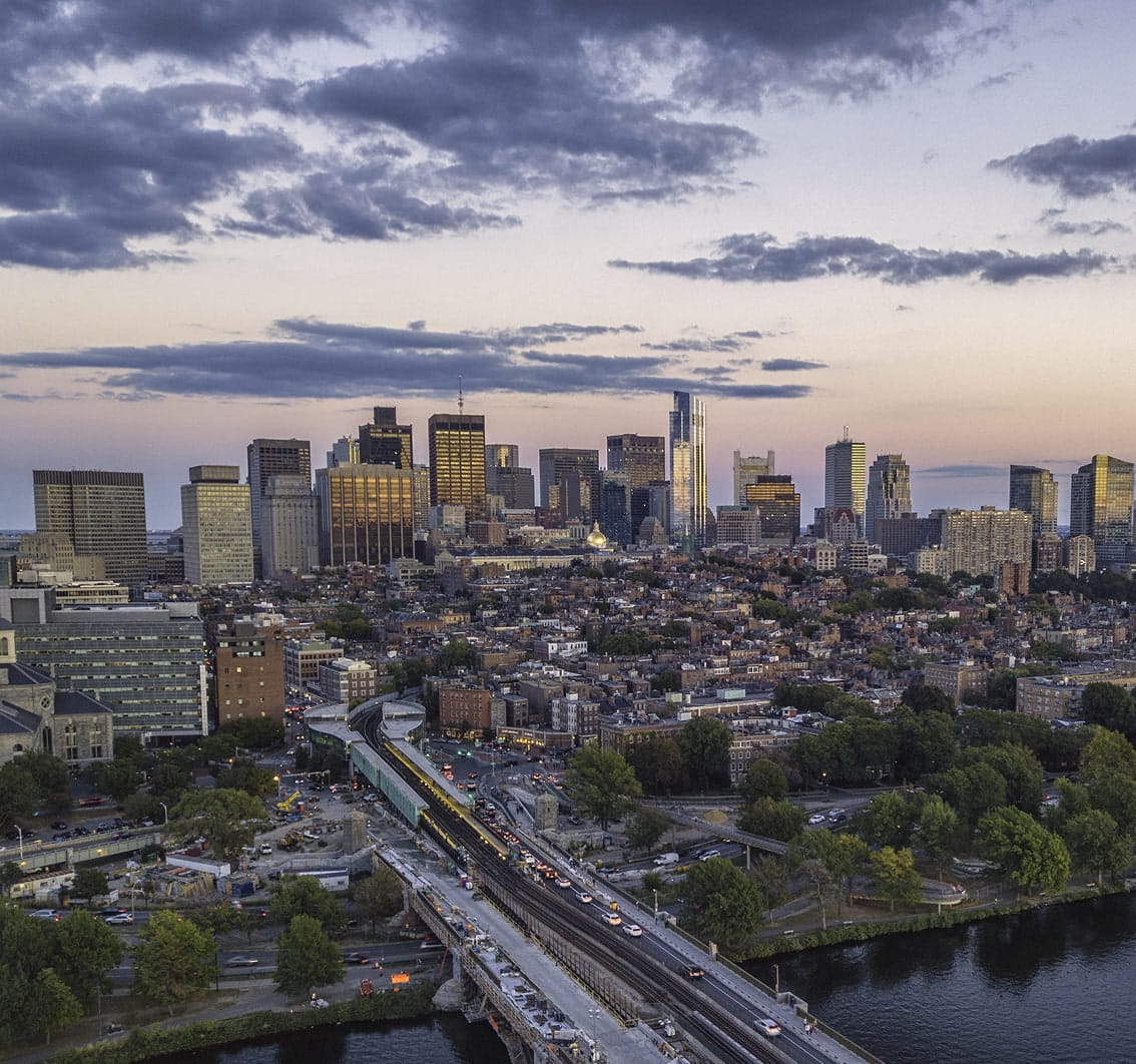 Vista aérea de Boston al atardecer con el tren y el puente sobre el río Charles.
