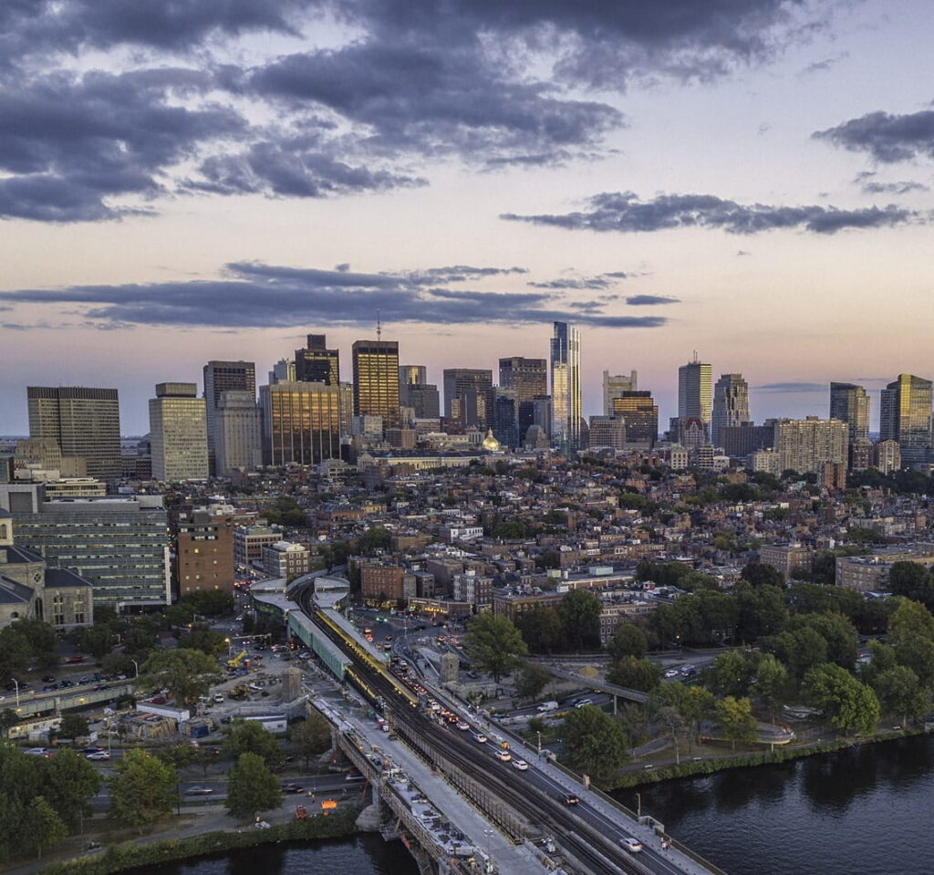 Vista aérea de Boston al atardecer con el tren y el puente sobre el río Charles.