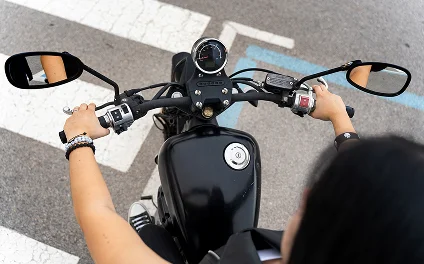 Motociclista sujetando el manubrio de una motocicleta negra al cruzar un paso peatonal
