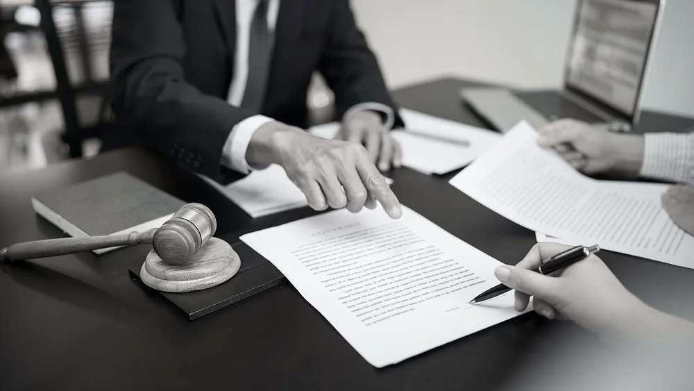 Abogado revisando documentos legales con un cliente que firma un acuerdo.