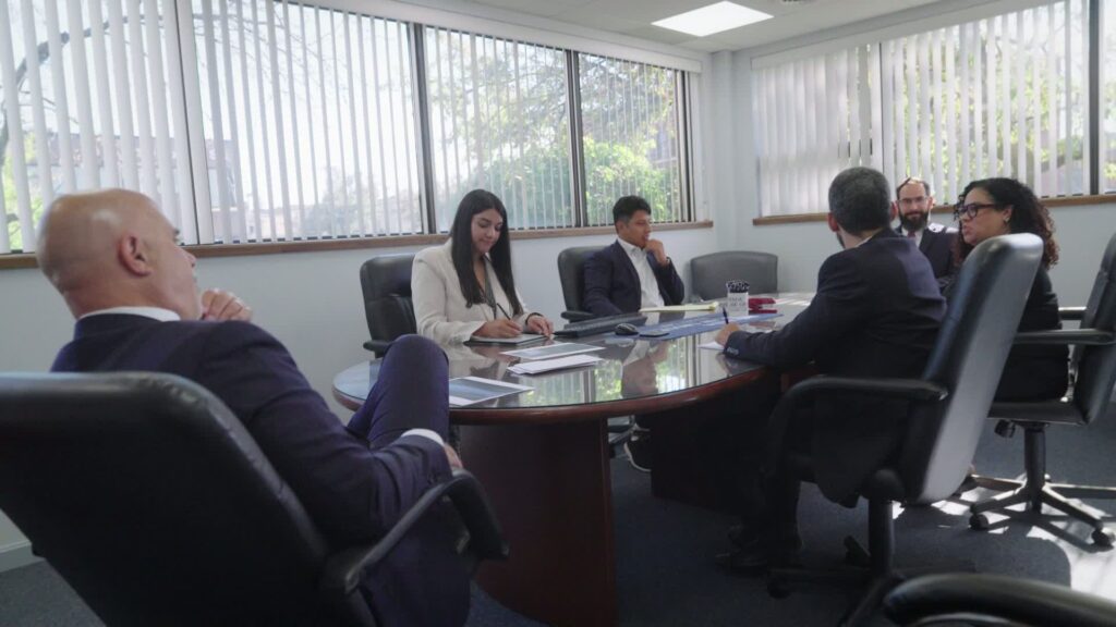 Equipo legal de El Abogado Spada reunido en sala de conferencias revisando un caso.